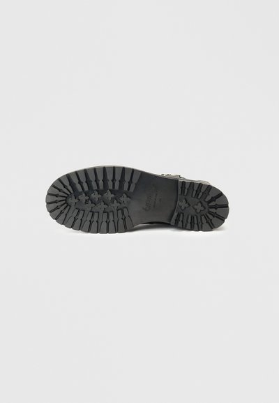 Sola de bota de borracha preta com sulcos profundos e padrão para tração. Inclui impressão da marca e detalhes de tamanho. Construção robusta para durabilidade.