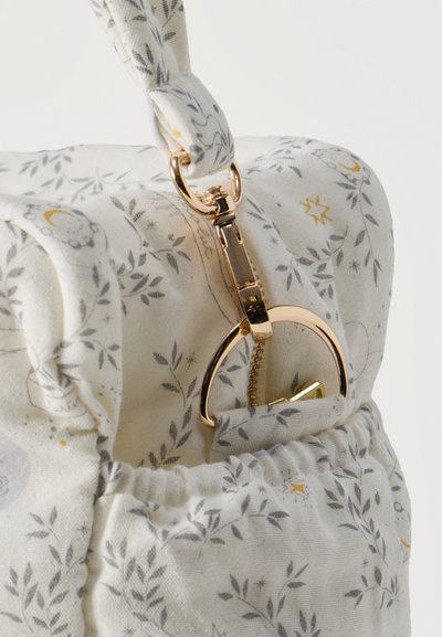 Približnji posnetek bele platnene torbe z vzorci sivih in zlatih nebeških listov ter z zlato kovinsko zaponko in obročem za ročaj.