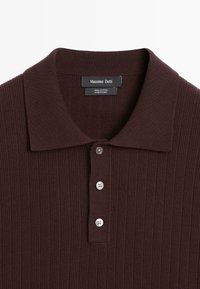 Polo à manches longues côtelé de couleur brun foncé, avec trois boutons et un col classique, étiqueté 100% coton par Massimo Dutti.
