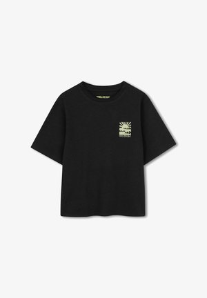 T-shirt noir à manches courtes avec un petit motif jaune représentant un soleil au-dessus des vagues et le texte « VOLTAIRE » sur la poitrine gauche.