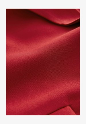 Tissu rouge avec une texture lisse, affichant un léger éclat. La surface est finement tissée, présentant des motifs subtils et une apparence structurée.