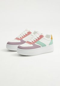 Zapatillas coloridas con una base blanca y acentos en rosa, verde y lavanda. El diseño incluye una puntera perforada, suela blanca gruesa y ojales multicolores.