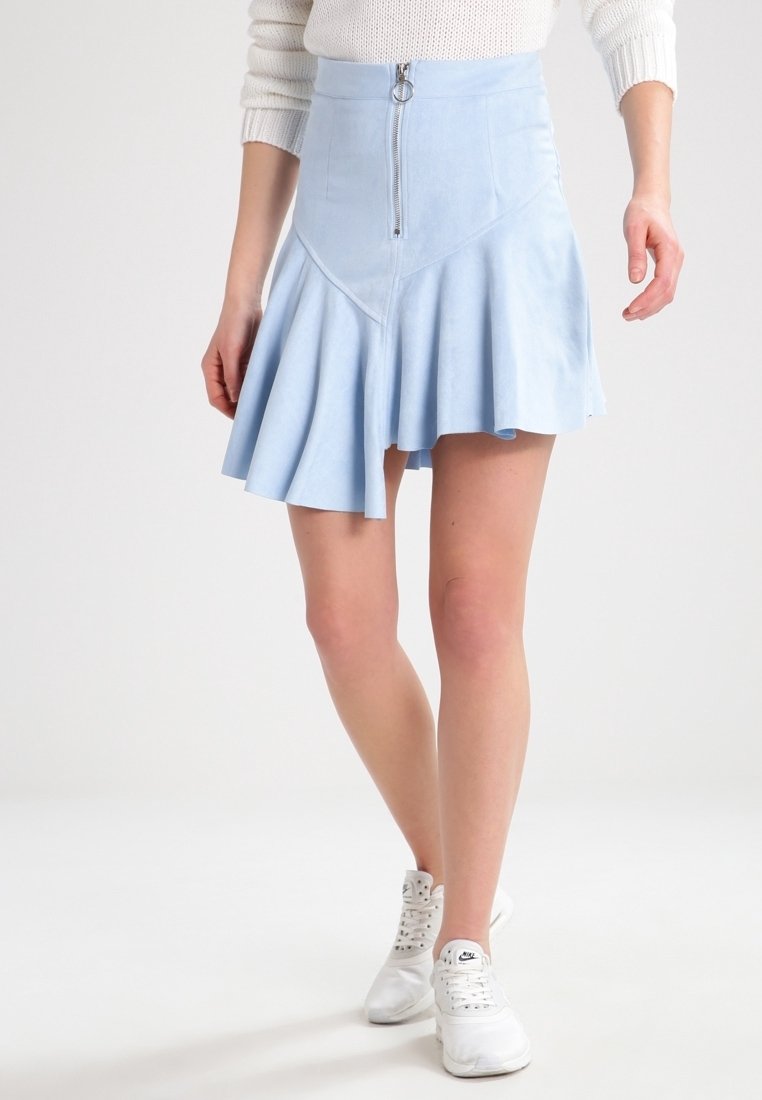 Vaaleansininen, liehuva hame, joka on valmistettu pehmeästä mokkanahkamaisesta materiaalista, edessä on vetoketju ja vinot saumat. Hame on yhdistetty valkoisiin urheilukenkiin.