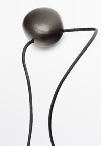 Black wooden pendant with a smooth, rounded shape, attached to a slender black cord. Simple design emphasizes minimalism and texture.