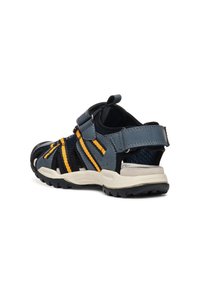 Sandales bleu marine avec des accents jaunes, bride ajustable, tige en mesh respirant, semelle en caoutchouc et design de capuchon de protection pour les orteils.