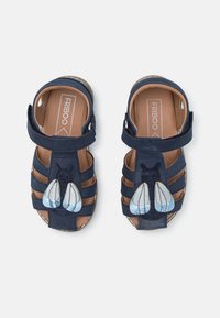 Chanclas azul marino con una correa, con un motivo de abeja con alas azules y blancas. Hechas de ante, diseño de punta abierta y plantilla acolchada.
