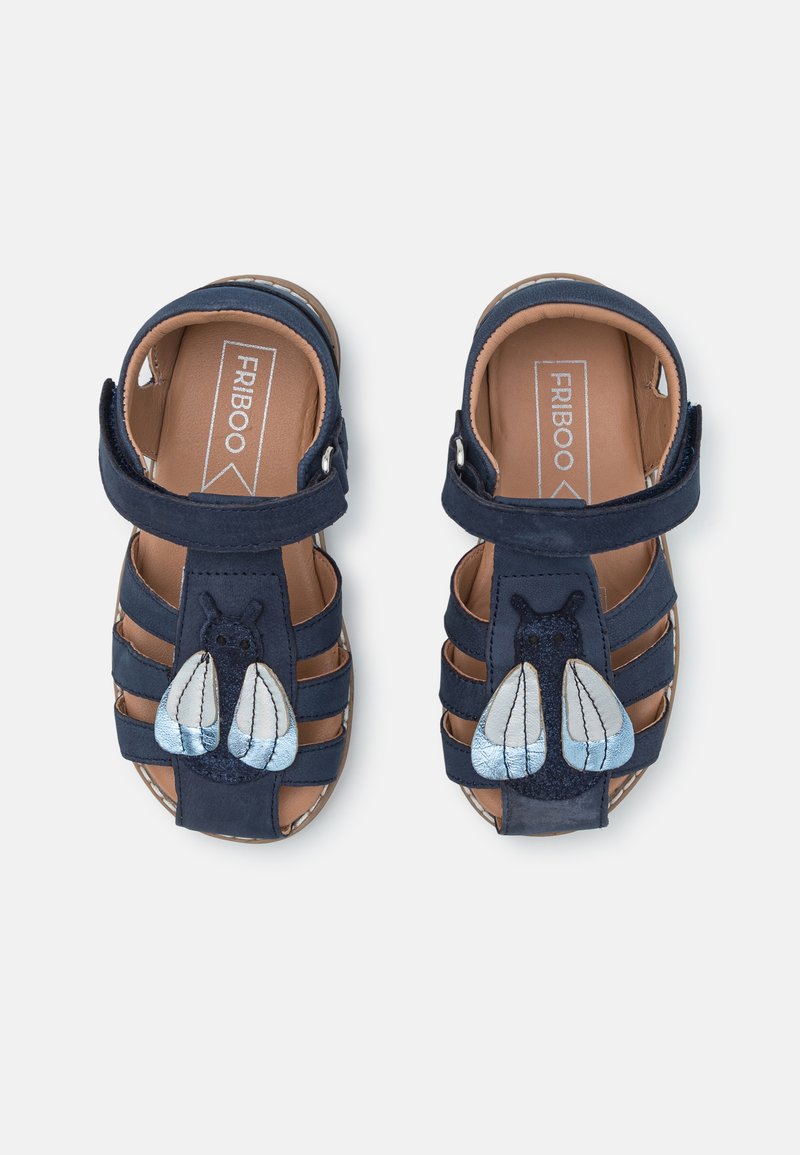 Chanclas azul marino con una correa, con un motivo de abeja con alas azules y blancas. Hechas de ante, diseño de punta abierta y plantilla acolchada.