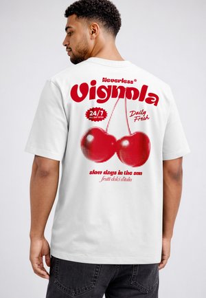 Man facing sideways wearing white t-shirt with large red cherries and text "Nevertheless Vignola 24/7 Daily Fresh slow days in the sun" on back.
