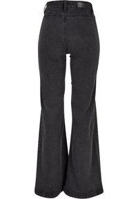 Jeans de campana negros con una textura de denim suave, cintura alta y detalles en el bolsillo trasero. Dobladillo limpio y etiqueta de marca sutil en la cinturilla.