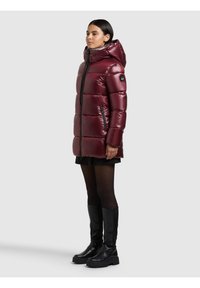 Viininpunainen toppatakki hupulla, vetoketjullinen etuosalla ja mustilla yksityiskohdilla. Siinä on vaakasuorat ompeleet, kaksi sivutaskua ja kiiltävä pinta.