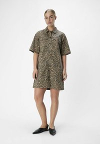 Korte mouwen, jurkje met luipaardprint in tan- en bruintinten, met een kraag, drukknoopjes en een relaxte pasvorm. Gecombineerd met zwarte platte schoenen.