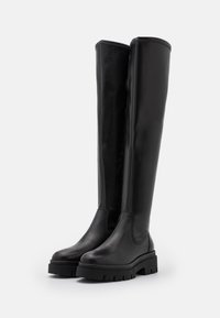 Botas negras hasta la rodilla hechas de cuero suave con suela gruesa y costuras laterales texturizadas. Presentan una punta redonda y un diseño limpio.