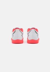 Zapatillas deportivas blancas con una parte superior texturizada, acentos naranjas en la suela y el talón, con un diseño elegante y detalles estampados en la parte trasera.