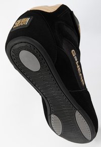 Melnas zamšādas sporta kurpes ar teksturētu zoli, ar zelta akcentiem un zīmolu uz papēža. Gluda purngala forma un mīksts dizains.