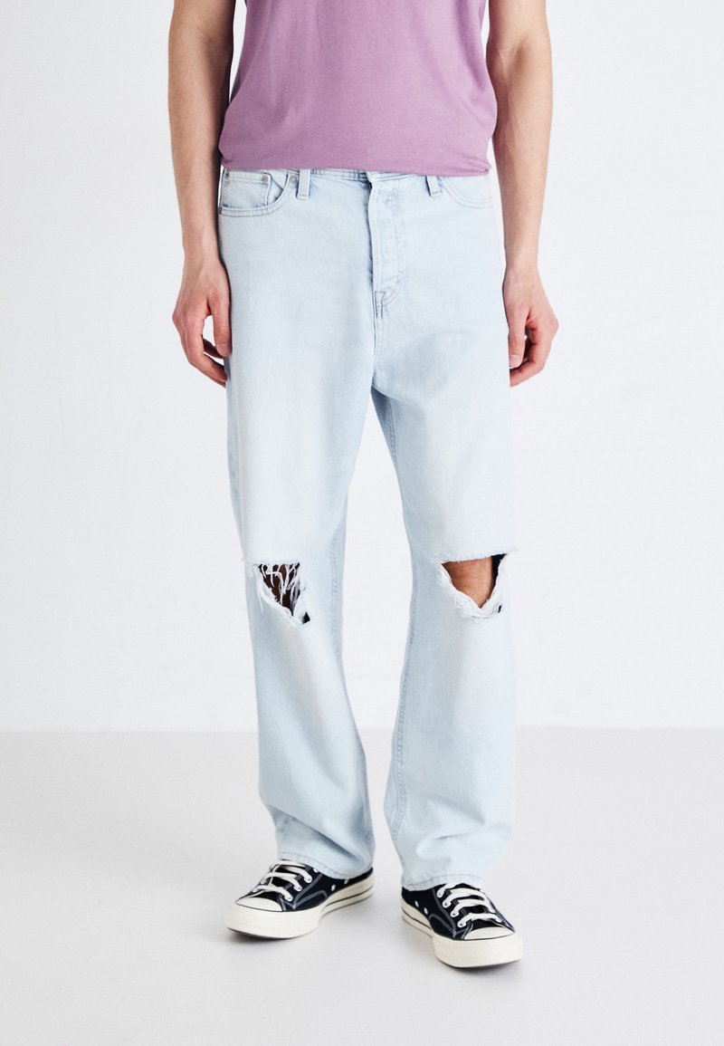 Light blue, distressed denim jeans with large rips at the knees. Straight leg design, featuring a classic five-pocket style and belt loops.