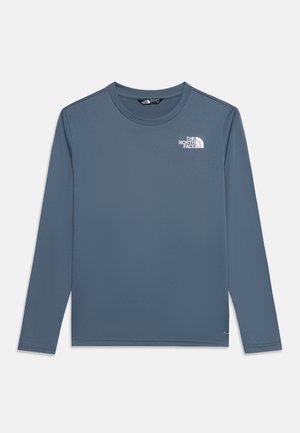 Niebieska koszulka z długim rękawem i okrągłym kołnierzem z białym logo The North Face na górnej lewej części klatki piersiowej, pokazana na jednolitym białym tle.