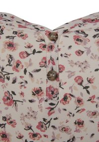 Stoff mit Blumenmuster in Creme, mit pinken und lila Blumen. Die Rückseite des Designs verfügt über einen Knopfverschluss mit einem glänzenden, runden Knopf.