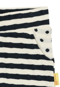 Striped cotton fabric in dark navy and cream with a pocket featuring black polka dots. Tag on side displays brand name.