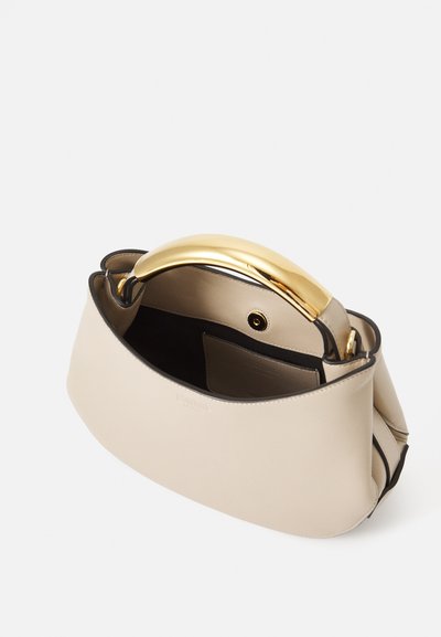 Sac à main en cuir beige avec une forme incurvée, poignée en métal doré et intérieur noir. Dispose d'une fermeture à pression et d'une poche interne.