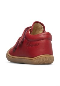Scarpa rossa in pelle con superficie strutturata, dotata di punta rotonda e suola in gomma morbida color sabbia. Strap in velcro nella parte superiore per la chiusura.