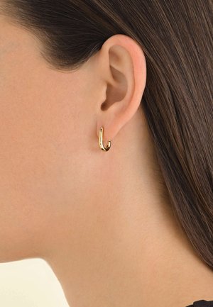 Gouden ringoorbel met een gebogen ontwerp, voorzien van een gladde, glanzende oppervlakte en een klein open lusdetail. Draagt op het oor.