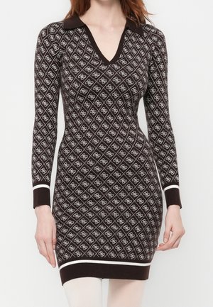 Femme portant une robe en tricot ajustée à manches longues avec un motif losanges marron et blanc et un col marron sur fond blanc.
