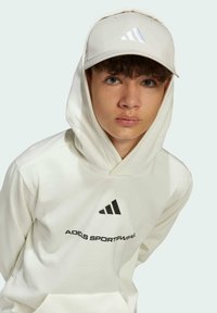 White hoodie with black "adidas" logo and three stripes. Light-colored cap with matching logo. Soft texture, casual design.