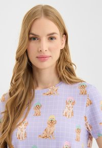 Lila overhemd met een rasterpatroon, met cartoonachtige honden die kleurrijke hoeden dragen. De stof lijkt licht en glad te zijn.