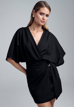 Black wrap dress with short batwing sleeves, a deep V-neckline, and a cinched waist featuring a silver accent. Smooth fabric texture.