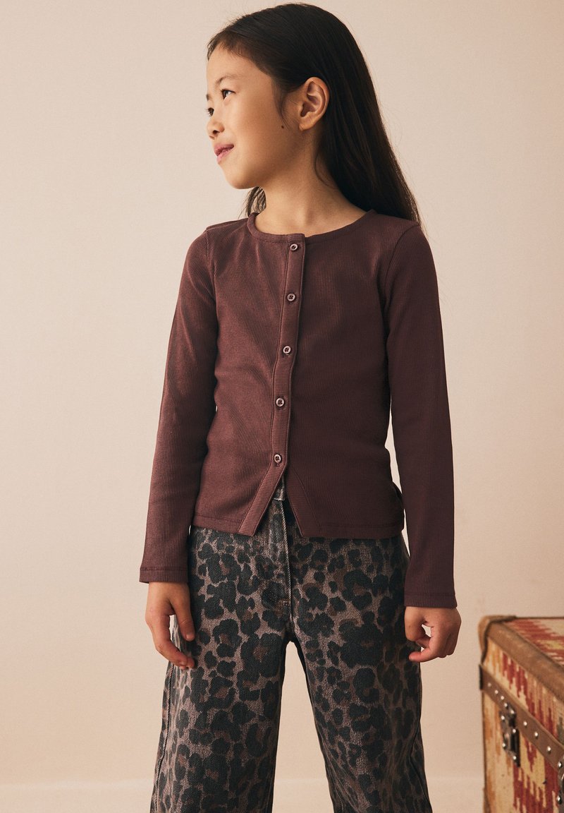 Haut à manches longues côtelé couleur marron avec fermeture à boutons sur le devant, associé à un pantalon large imprimé léopard gris. Tenue simple et décontractée pour enfants.