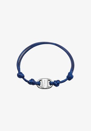 Bracelet en corde tressée bleue avec fermoir en argent, présentant des détails de nœuds et une finition polie. Nom de la marque gravé sur le fermoir.