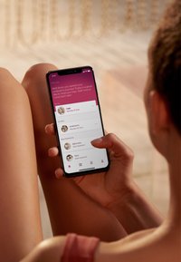 Smartphone au design noir élégant, affichant une interface utilisateur rose avec des rappels de traitement. Personne tenant l'appareil avec une peau bronzée.