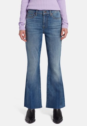 Jean en denim bleu évasé avec une finition décolorée, doté d'un design classique à cinq poches et d'un ourlet brut à la cheville.
