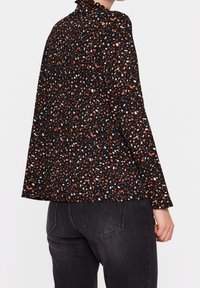 Camicia nera con un motivo sparso di punti arancioni, bianchi e blu, con un collo arricciato e maniche lunghe.