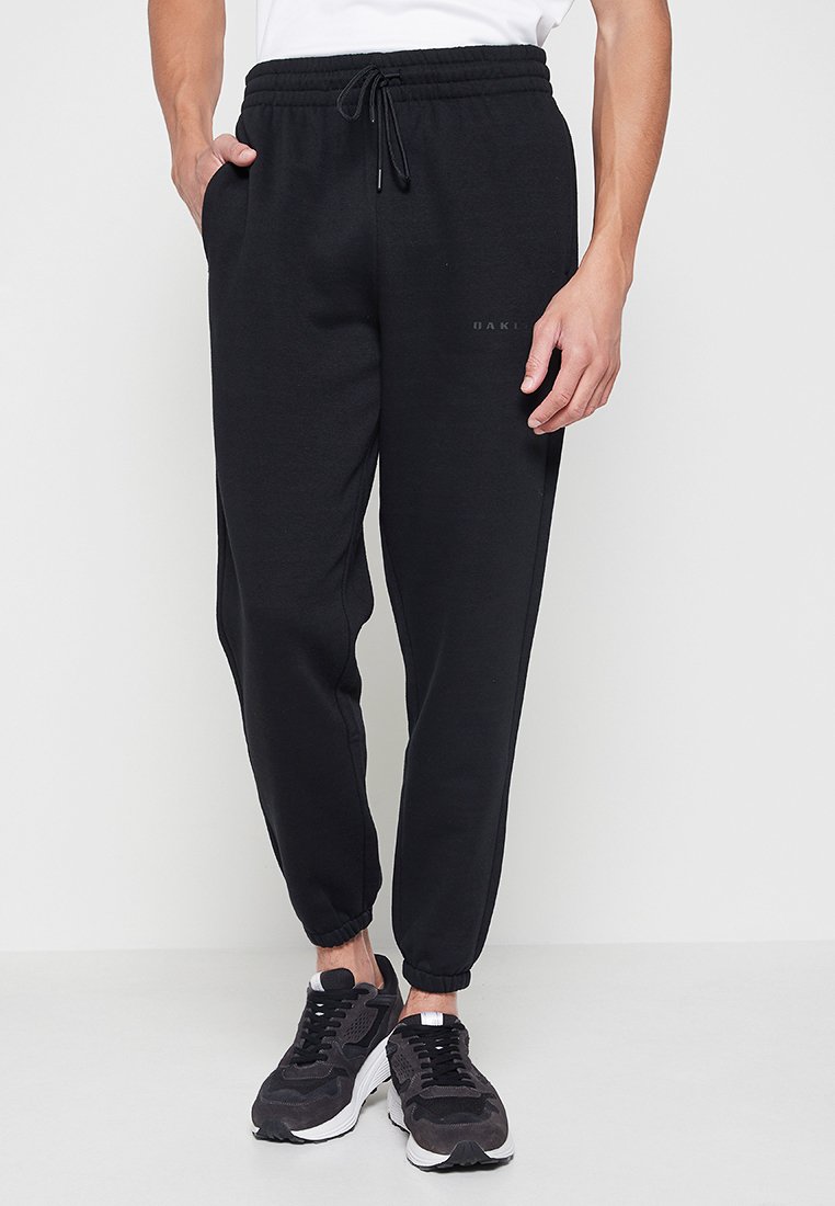 Czarne dresowe spodnie z elastycznym pasem i troczkami, z bocznymi kieszeniami i elastycznymi mankietami przy kostkach.