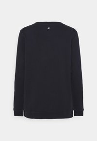 Sweat-shirt noir à manches longues vu de dos avec un petit logo blanc près de l'encolure sur un fond clair uni.