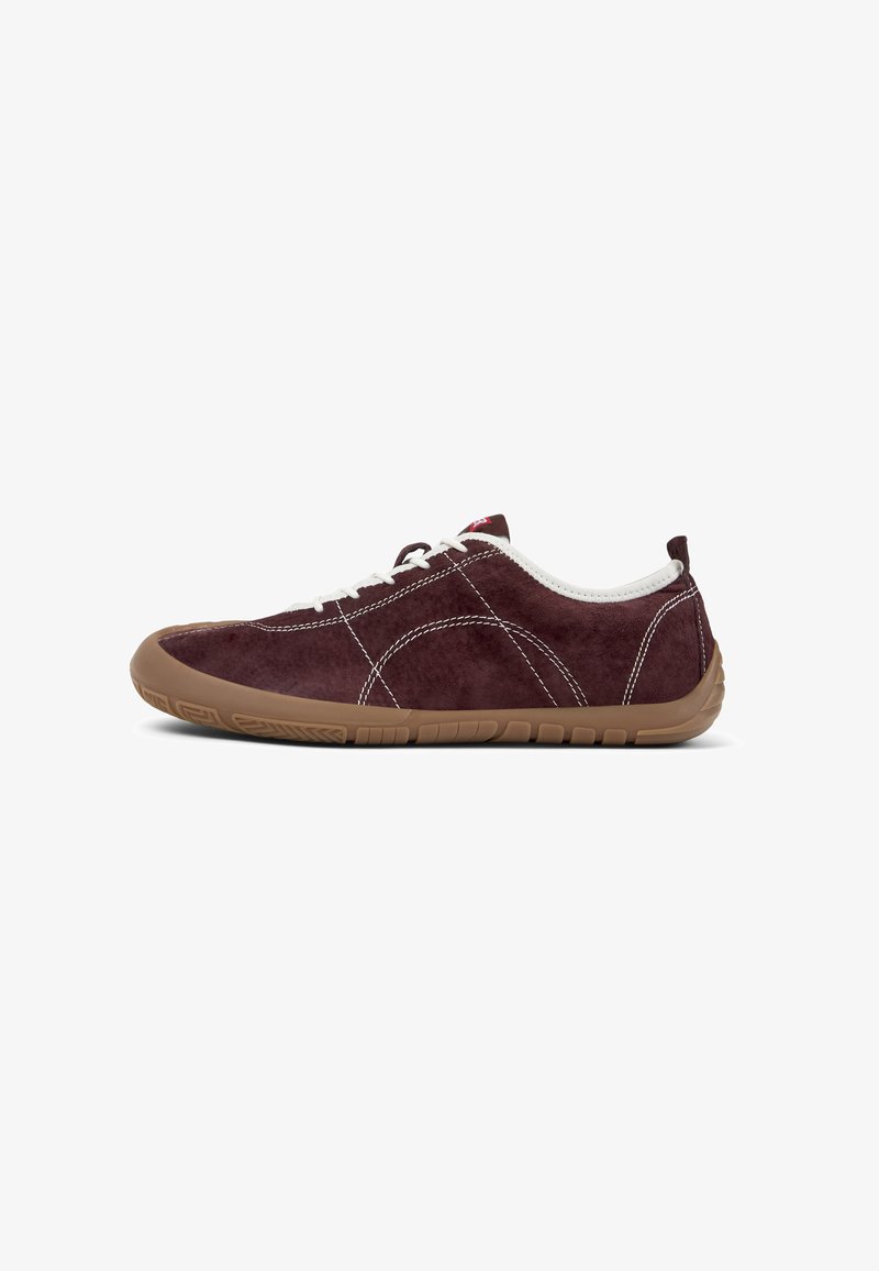 Burgundy suede sneaker with white laces, featuring a rubber sole and textured detailing. Side view, highlighting its casual design.