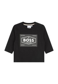 T-shirt noir à manches longues avec col rond, présentant un design graphique en blanc avec du texte et des motifs géométriques sur le devant. Fermetures à pression sur l'épaule.