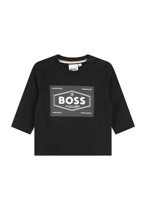 T-shirt noir à manches longues avec col rond, présentant un design graphique en blanc avec du texte et des motifs géométriques sur le devant. Fermetures à pression sur l'épaule.