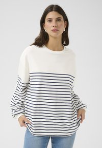 Striped pullover sweatshirt in cream and navy, with a crew neckline, long sleeves, and a logo patch at the hem. Soft cotton blend texture.