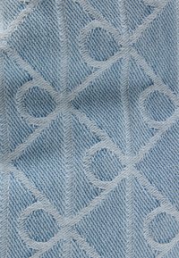 Φωτεινό γαλάζιο ύφασμα με γεωμετρικό μοτίβο από αλληλοεπικαλυπτόμενους βρόχους και διαγώνιες γραμμές. Το υλικό φαίνεται υφαντό με απαλή υφή.