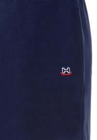 Pantalones cortos de color navy hechos de algodón, con un pequeño logotipo bordado en rojo y blanco en el lado izquierdo. Textura suave, diseño casual.