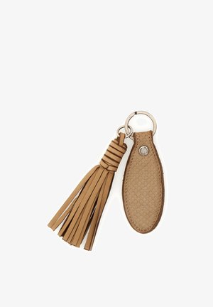 Portachiavi in pelle color cuoio con nappina intrecciata e targhetta ovale di tessuto, attaccati a un anello metallico con cuciture visibili e piccolo bottone metallico.