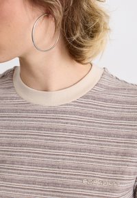 Kortærmet, lysebrun stribet t-shirt med en beige rund hals, lavet af tekstureret stof. Har broderet branding på brystet.