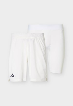 Twee paar witte sportkorte broeken opgestapeld, het voorste paar met elastische tailleband en Adidas-logo, het achterste paar in strakke compressiestijl.