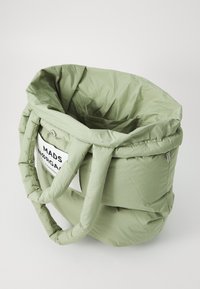 Sac fourre-tout rembourré vert avec une texture douce, doté de grandes poignées et d'une étiquette imprimée. Le design est rond et spacieux.