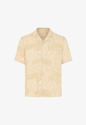 Chemise beige à manches courtes avec des boutons, arborant un motif patchwork subtil de cachemire et de bandana, et un col de style camp.