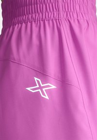 Fuchsia sportsbukser med elastisk talje, der har et hvidt logo og skrå sømdetaljer. Blødt, let materiale.