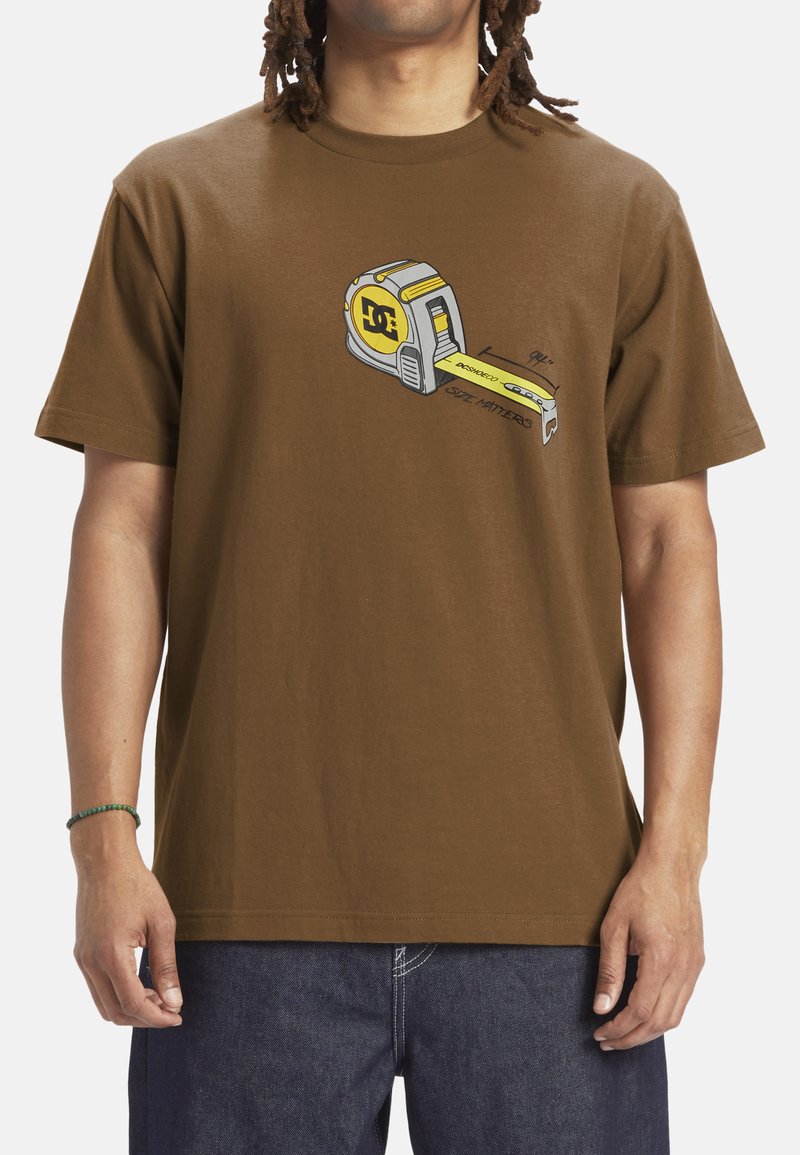 Brown cotton t-shirt featuring a graphic print of a gray and yellow tape measure. Short sleeves, crew neck, relaxed fit.