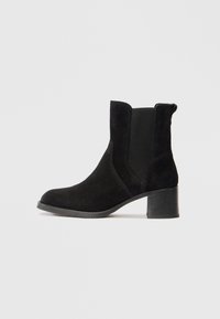 Stivaletti neri in suede con punta tonda, pannelli laterali elasticizzati e tacco a blocco texturizzato. Finitura liscia con dettagli di cucitura sottili.